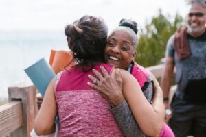 Two people embrace outdoors, with another person nearby.